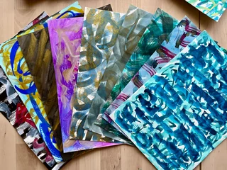 A fan of hand-painted cover papers with blue, gold, gray and violet brushwork