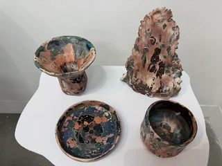 Sculptural ceramic forms displayed on a white plinth